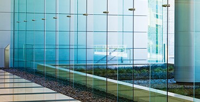 Exterior windows on a government building reflect sunlight.
