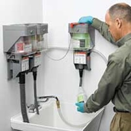 Un trabajador de limpieza mide productos químicos de limpieza con el Sistema de Dispensación Twist 'n Fill de 3M.
