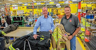Employees of Globe Manufacturing Company, holding firefighter jackets, equipped with 3M Scotchlite Reflective Material