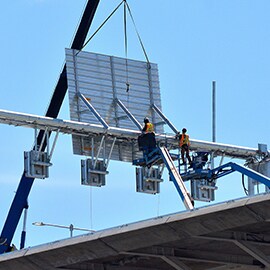 Maintenance workers attending to overhead road sign.