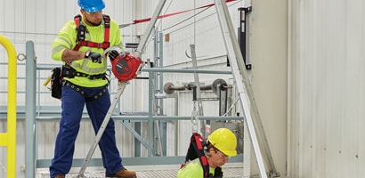 Workers demonstrating portable confined space retrieval tripod 
