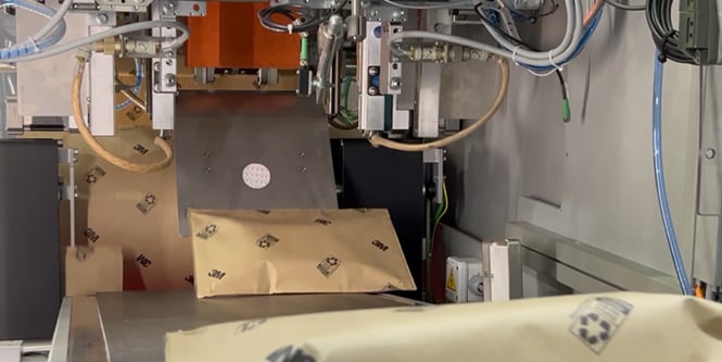 Empaque de papel pasando por una máquina automatizada.
