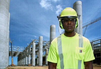 Trabajador de la construcción con casco, gafas de protección y protector auditivo 3M.
