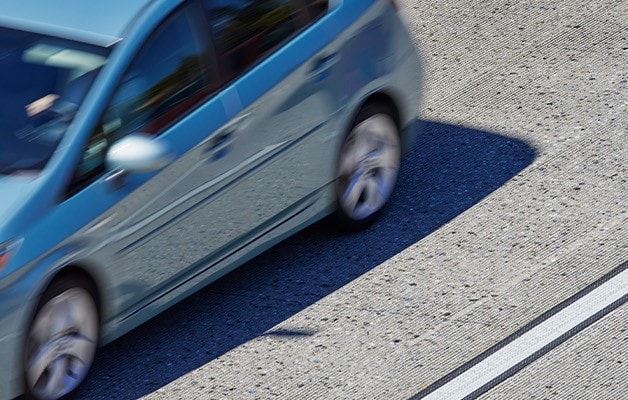 Auto azul circulando por una carretera con marcaje vial de alto contraste