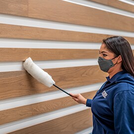 Employee dusting wooden wall feature.