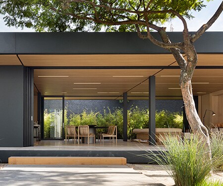 Exterior de una casa moderna con acabados en negro mate y madera clara.
