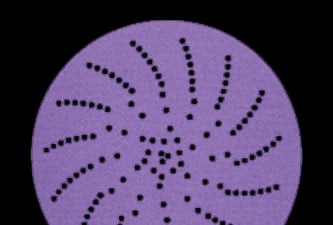 Un disco de lijado circular de color morado con un patrón en espiral denso de pequeños orificios de extracción de polvo en toda su superficie.

