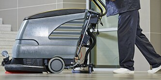 Imagen donde se muestra medio cuerpo hacia abajo de una persona utilizando la máquina de lustrador de piso.
