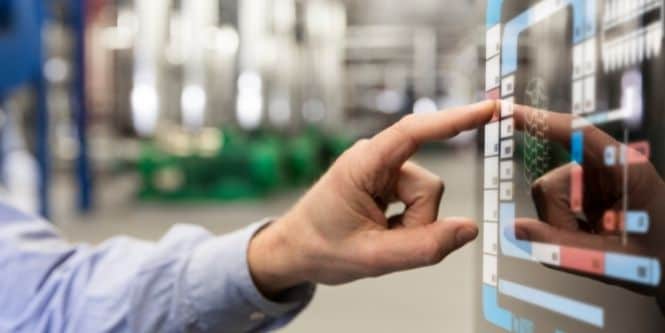 Imagen de un trabajador de fábrica utilizando una pantalla táctil en la línea de ensamblaje.
