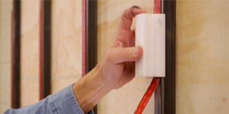 A worker unrolls 3M™ VHB™ Tape on a vertical bar while using a 3M™ Hand Tape Applicator in the other hand to apply pressure
