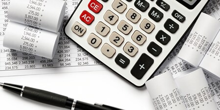Una calculadora rodeada de recibos impresos y gráficos.
