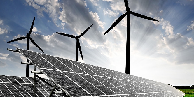 Paneles solares en primer plano y tres turbinas eólicas al fondo bajo un cielo parcialmente nublado, representando generación de energía renovable.
