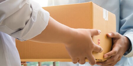 Una persona entregando una caja de cartón a otra persona.
