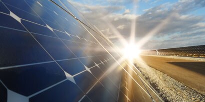 Solar panels producing solar energy with a sun in the background

