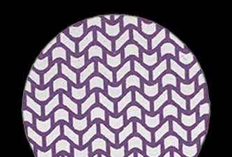Un disco abrasivo circular con un patrón repetitivo de chevrón morado que cubre toda la superficie.

