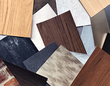 Colección de muestras de acabados para superficies con diferentes vetas de madera, tonos metálicos y patrones.
