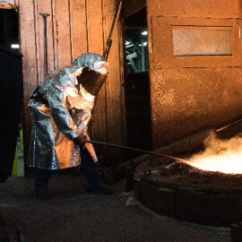 Trabajador con equipo de protección personal trabajando en un proceso de fundición.