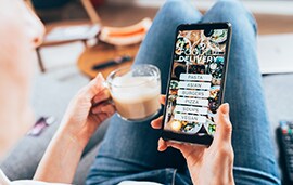 woman looking at her phone with a take-out and delivery app displayed.