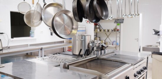 Una cocina con ollas y sartenes desde el techo.
