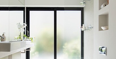 The windows in a brightly lit room have a decorative window film, adding beauty while enhancing privacy.
