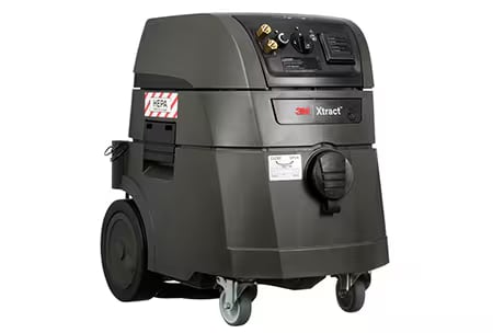 Un extractor de polvo 3M Xtract de color gris oscuro con ruedas traseras grandes, ruedas giratorias delanteras, panel de control superior y etiqueta de filtro HEPA en el lateral.
