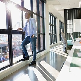 A man standing and looking out of a window with a light control film installed.