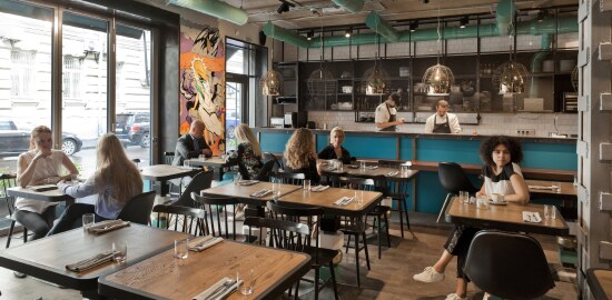 Un restaurante con algunos clientes sentados en las mesas.

