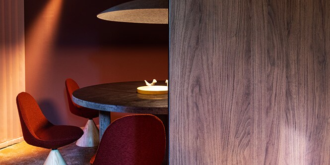 Comedor con mesa redonda revestida con Acabado Arquitectónico metálico 3M DI-NOC, así como paredes con acabados arquitectónicos en color mate y madera oscura.
