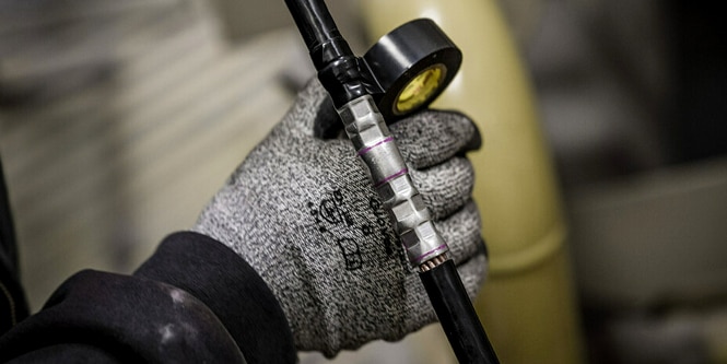 Un trabajador envolviendo un empalme eléctrico de forma irregular con la cinta Super 33+.
