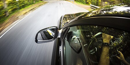 Un hombre conduce un coche por una carretera.
