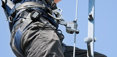 Worker climbing tower ladder connected to cable ladder safety system
