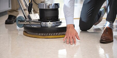 Employee inspecting a recently polished floor.
