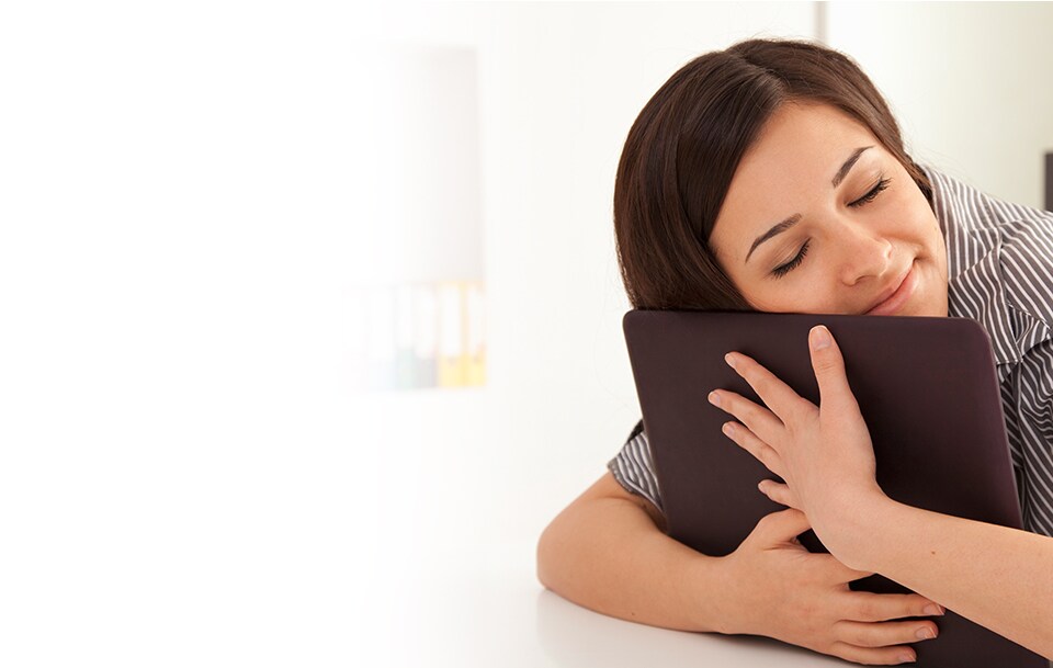 Image of a woman hugging her laptop, happy to have a privacy filter.