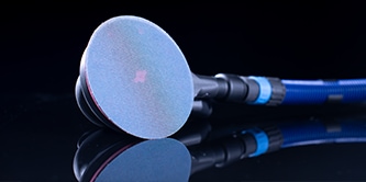 Acercamiento de una lijadora  con un disco abrasivo azul, mostrada sobre una superficie oscura y reflectante.
