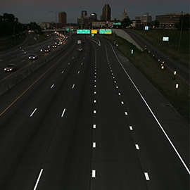 Fotografía nocturna de una autopista tomada desde arriba con marcas en el pavimento que muestran una reflectividad brillante.