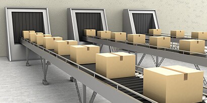 Imagen de tres cintas transportadoras llenas de cajas cerradas.
