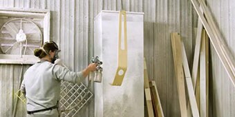A worker sprays a scooter part before assembly
